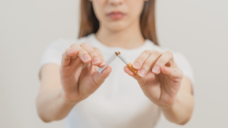 woman breaking cigarette in half