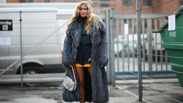 Woman wearing gym shorts, fur coat