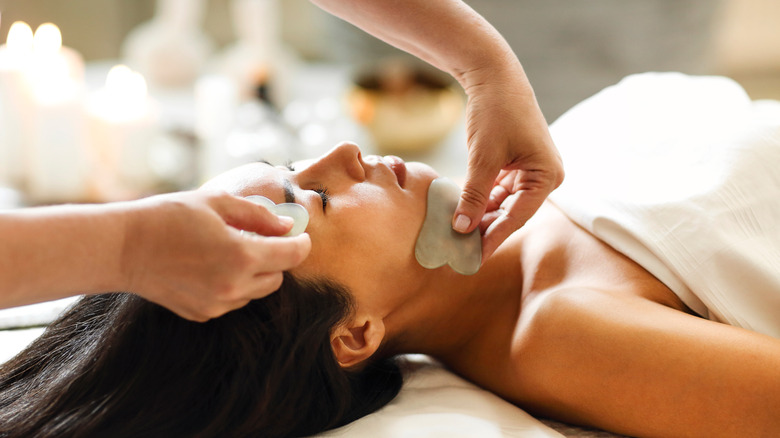 woman at a spa getting a gua sha facial treatment