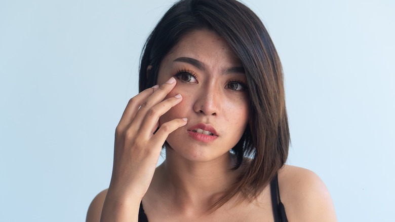Woman touching irritated eye