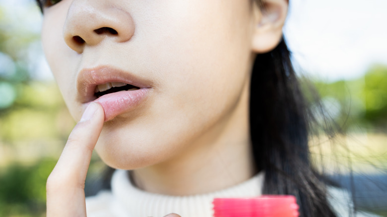 woman applying balm to lips