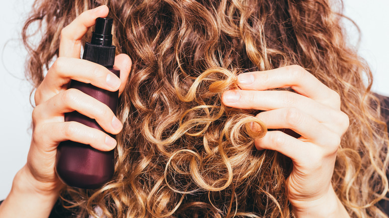 Woman spraying curly hair