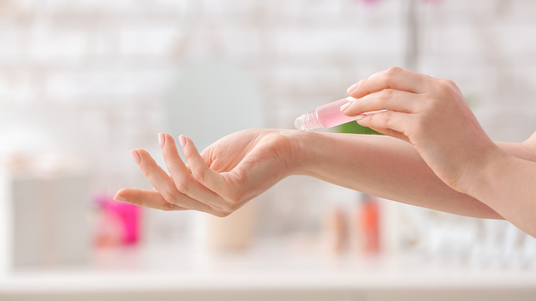 hands applying roller ball fragrance