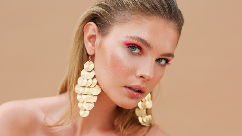 Model wearing large gold earrings
