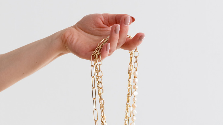Hand holding dangling gold necklaces