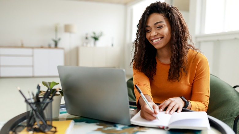 woman writing near laptop
