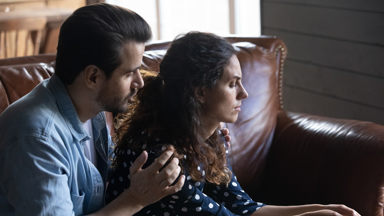husband sitting behind his wife holding and comforting her