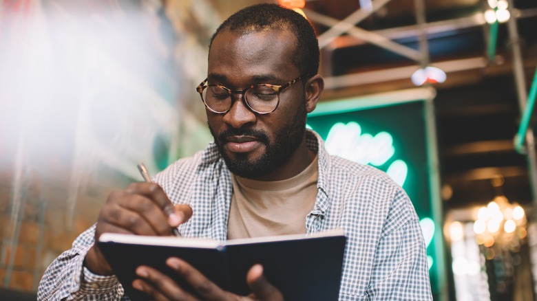 man writing in a journal