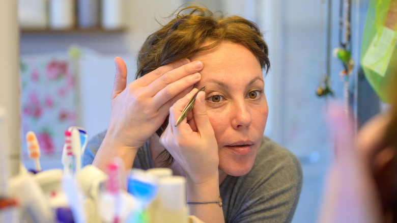 woman tweezing eyebrows