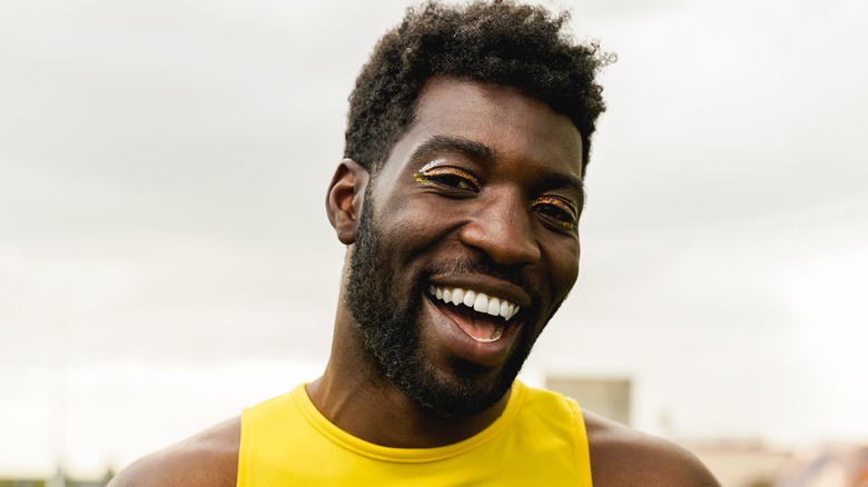 Man wearing yellow eye makeup