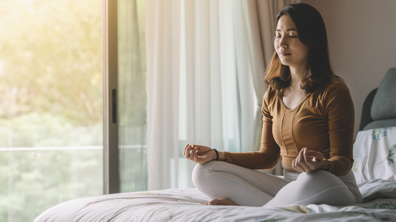 woman meditating on bed
