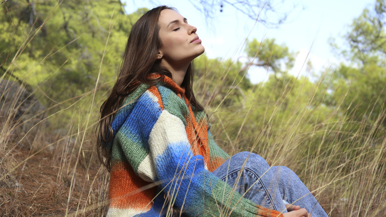 A woman sitting outside and taking a deep breath