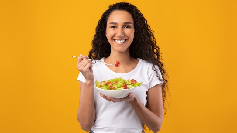 Woman eating bowl of vegetables