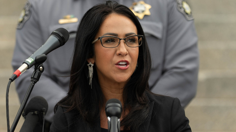 Lauren Boebert speaks to reporters wearing a purple dress and black blazer jacket