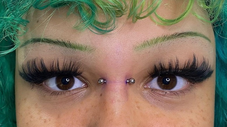 Close up of newly-pierced bridge piercing