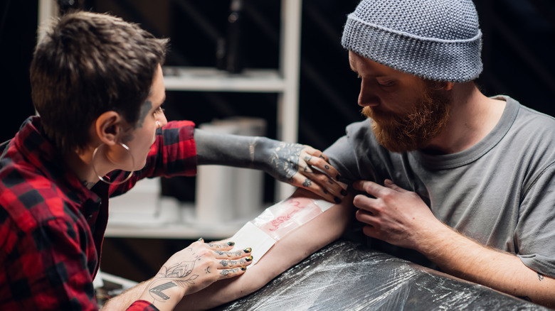 tattoo artist wrapping client's finished tattoo