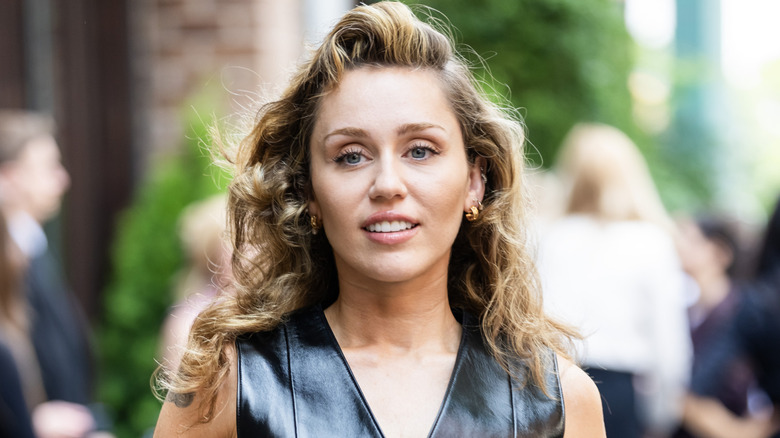 Miley Cyrus' face with a head of curls and a small smile