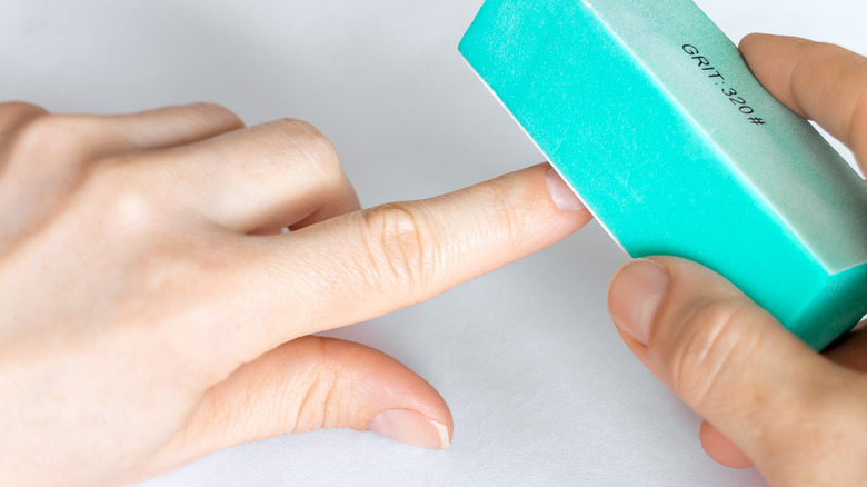 Hands using buffer block on fingernails