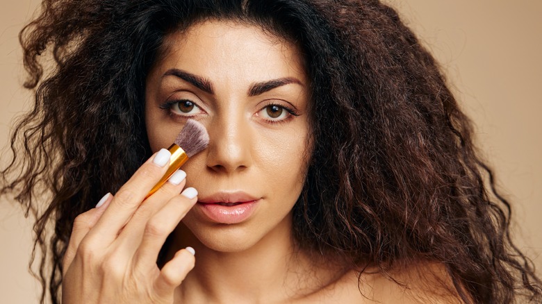 woman applying powder under eyes