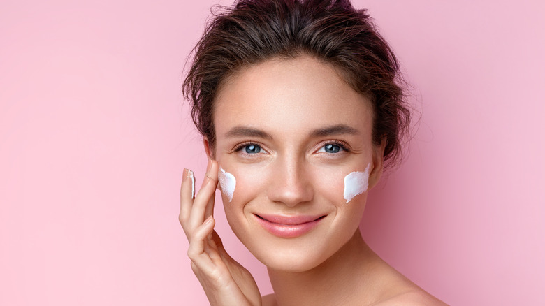 Woman applying moisturizer 