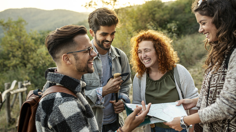 Four people smiling and looking at map outside