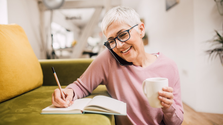 older woman taking notes phone call