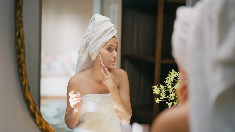 Woman shaving his face while looking in the mirror