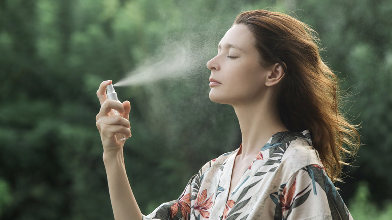 woman spraying sunscreen on her face