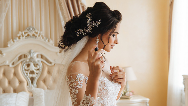 Bride applying perfume on neck 