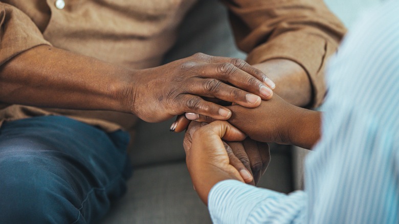 Close-up of man and woman holding hands
