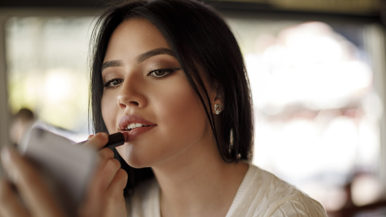 woman applying pink lipstick