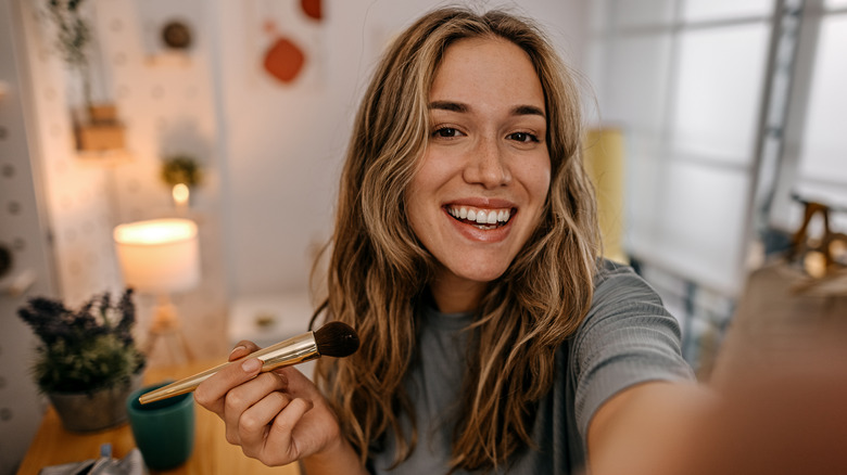 smiling woman applying makeup