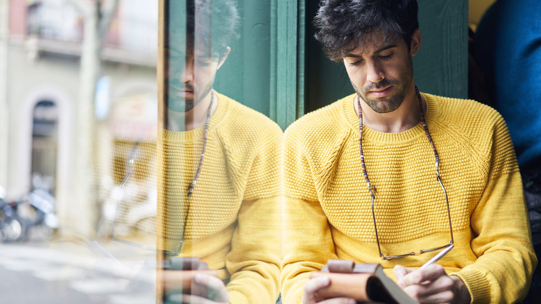 Man sitting near window writing