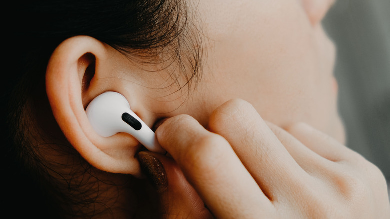 woman putting airpod in ear