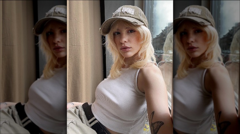 Woman wearing white tank, hat