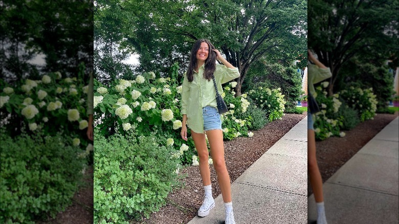 Girl wearing a button down top with denim shorts.