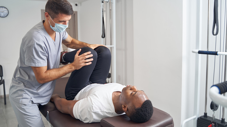 Doctor helping injured man stretch