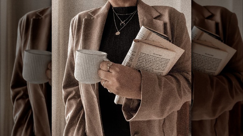 Girl holding coffee and books.