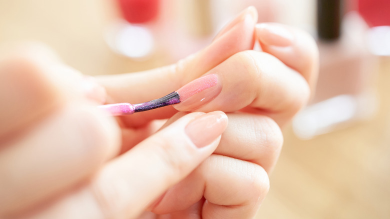 A woman applying nail polish to her nails.