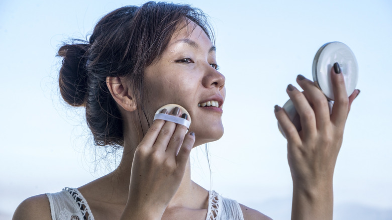 woman applying powder sunscreen 