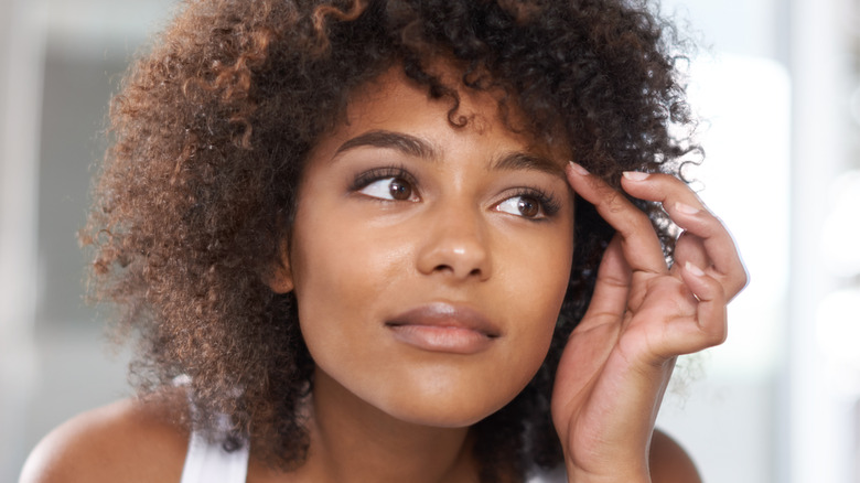 A woman examining her eyebrows in the mirror.
