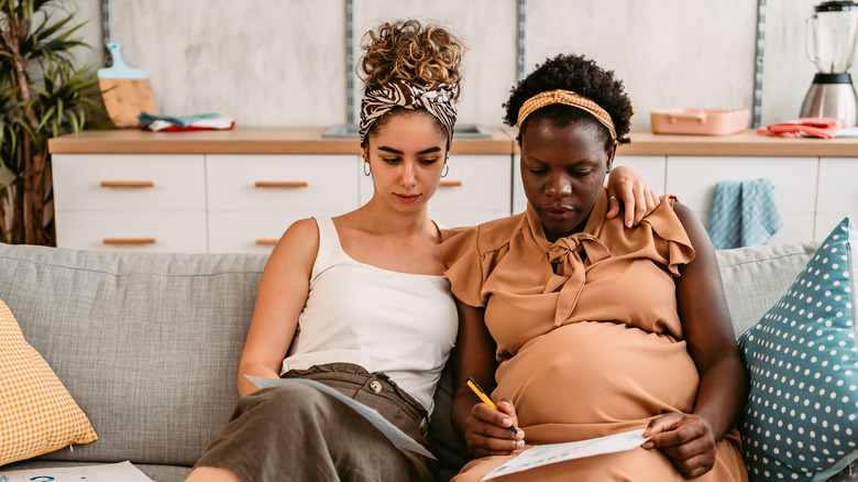 Women couple pregnant sitting on sofa
