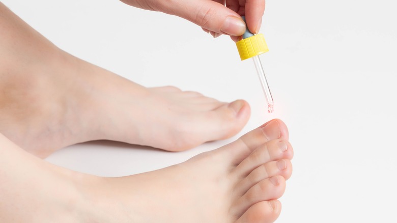 woman applying cuticle oil to feet