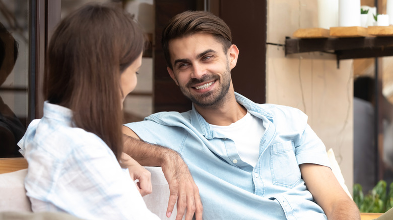 Young man and woman sitting close, smiling