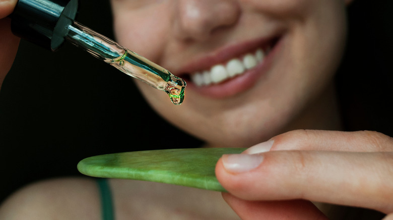 woman applying serum to gua sha