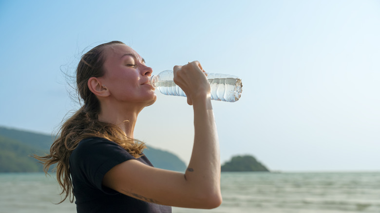 Woman drinking bottle of water on the beach
