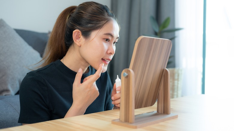 A woman applying acne cream