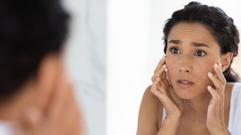 Woman looking in mirror, worried