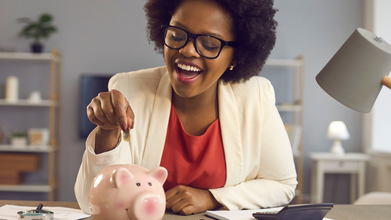 Woman dropping coin into piggy bank
