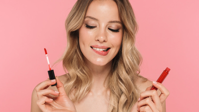woman holding up lipgloss and lipgloss brush
